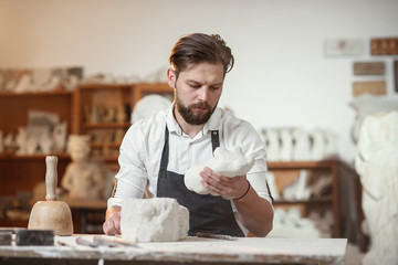 Craftsman hands working with stone sculptor at creative workplace in the atmospheric studio.