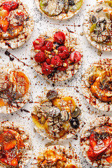 Rice wafers with a variety of fresh fruits, seeds, nuts and cream cheese sprinkled with chocolate sauce on a white background, top view. Rice cakes, the concept of a healthy breakfast or dessert