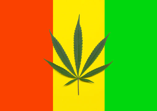 Green cannabis leaf isolated on rastafarian colored flag. Marijuana leaf isolated