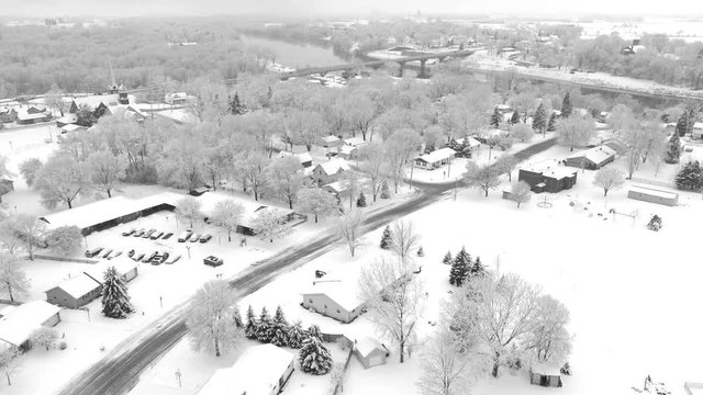 Very scenic small town neighborhood, trees covered with snow, homes blanketed in white, aerial drone view.