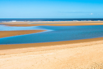 Tide pool of water at low tide on Barnham Overy Staithe beach in North Norfolk, East Anglia, England, UK.