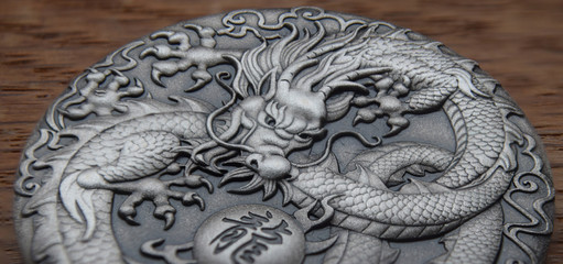 Macro of a dragon on a silver coin with chinese writing saying "Dragon"