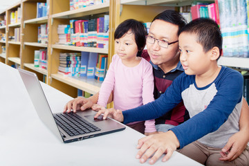 Father helps his children to learn with a laptop