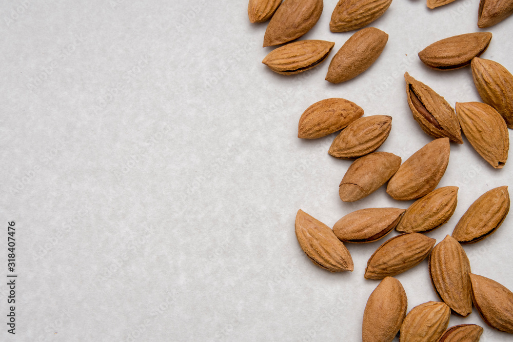 Wall mural Dried almonds are scattered on a Board-stand on a gray background, healthy food for raw foodists and vegetarians, nuts and dried fruits.