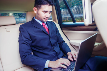 Handsome man looking his laptop inside car