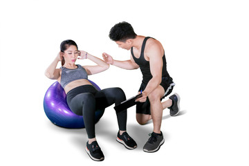 Obraz premium Male trainer helping young woman doing workout
