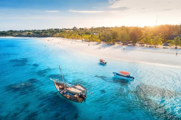 Selbstklebende Fototapete Zanzibar Luftaufnahme der Fischerboote an der tropischen Küste mit Sandstrand bei Sonnenuntergang. Sommerurlaub in Sansibar, Afrika. Landschaft mit Boot, Yacht im transparenten blauen Wasser, grüne Palmen. Ansicht von oben