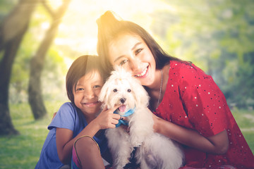 Woman and her daughter hugging a maltese dog