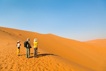 Family climbing up red sand dune