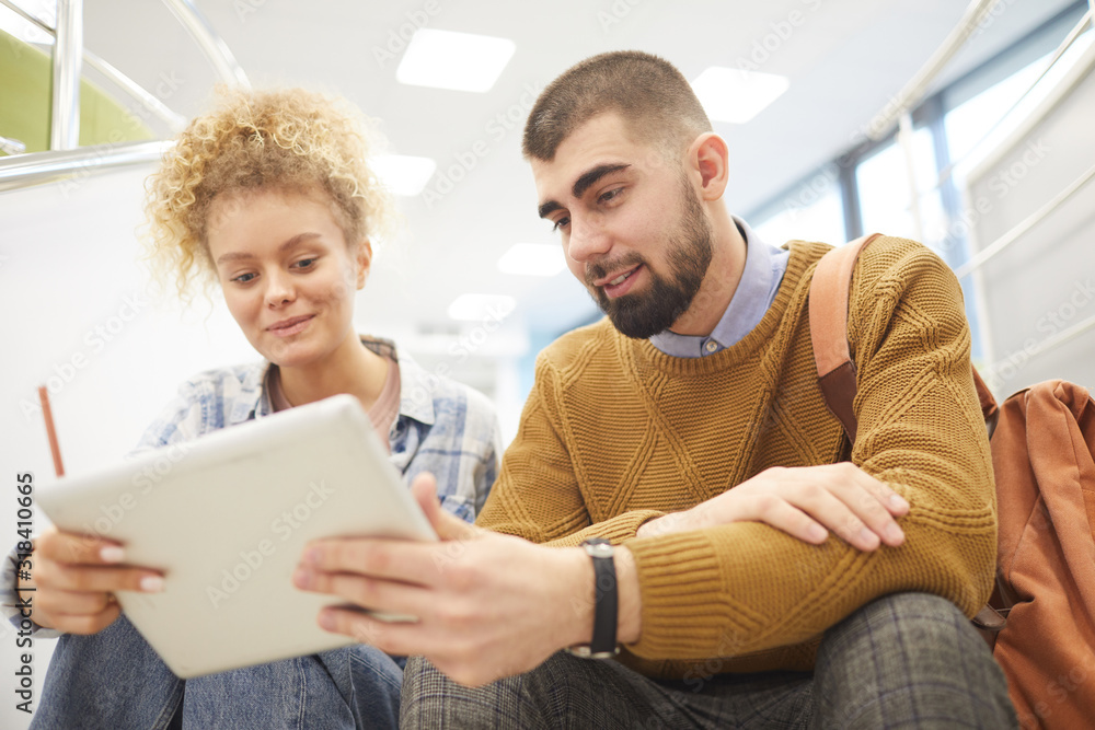 Wall mural low angle portrait of student couple using digital tablet together while working on project in moder