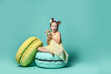 Cute little girl in bright yellow dress have fun at birthday waffles cone with tasty raspberry marshmallow and huge cake sweets 