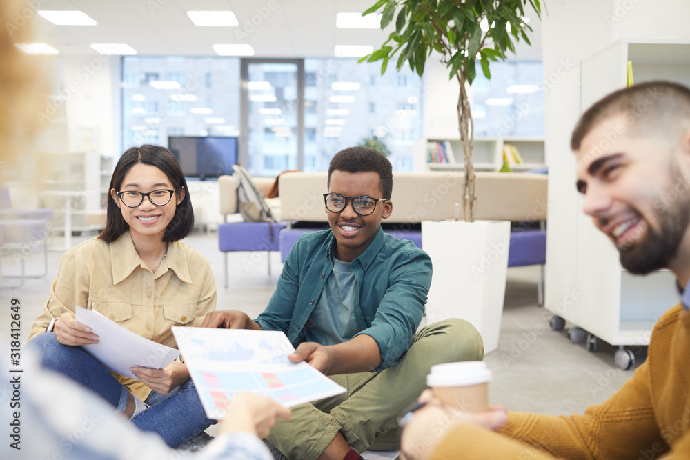 Wall mural multi-ethnic group of students smiling cheerfully while working on project in college library, copy 