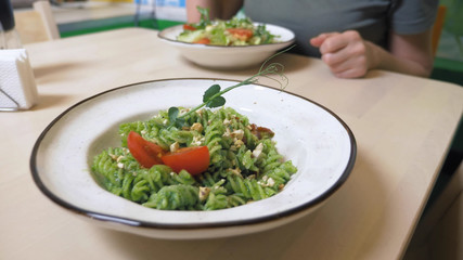 a vegetarian lunch. vegetable salad and pasta with a green sauce.