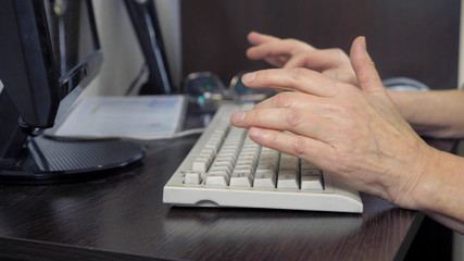 closeup hands of an elderly woman typing on a keyboard