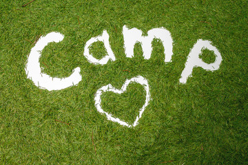 The word Camp. Pine needle lining. Ecology concept. Hands draw. Image on a green background.