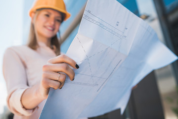Professional architect holding blueprints outdoors.
