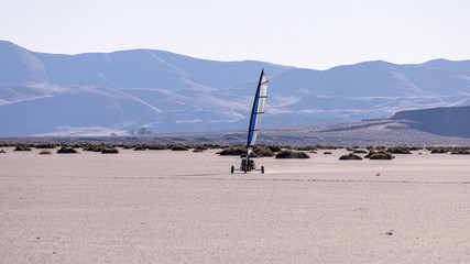 Land sailing in Alvord desert, Oregon. A blow cart surfing across playa,  Steens mountains in the background