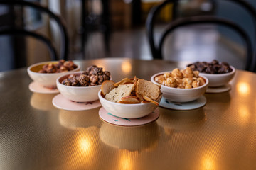 Five white bowls i filled with snacks - caramel and chocolate popcorn, peanuts, bread and chips on a table