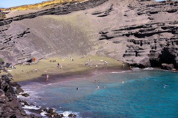 People on a Green Beach, Big Island Hawaii. Papakōlea Beach is a green sand beach located near South Point, one of four green beaches in the world.