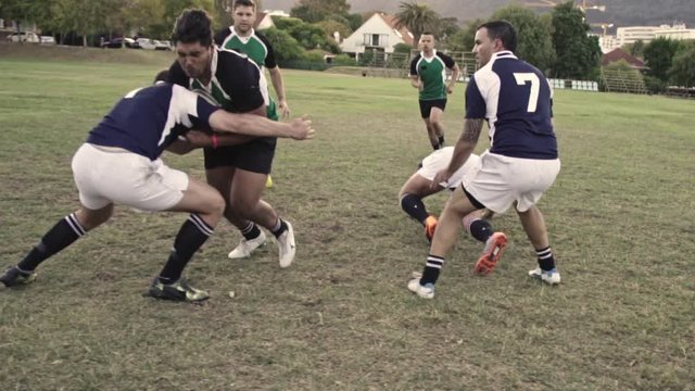 Rugby players tackling for ball possession during the match. Young men playing intense game of rugby.