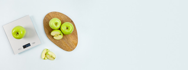Fresh green apple on gray digital kitchen scales. Near some apples on wooden board. Healthy eating habits. Weighing products. Flat lay, copy space. Kitchen equipment. Healthy food and diet concept. 