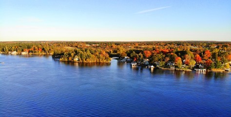 Fototapeta na wymiar The aerial view of the residential area and waterfront homes surrounded by colorful fall foliage near Wellesley Island, New York, U.S.A