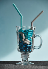 Medicine Blue and white capsules in the cocktail glass on the blue background