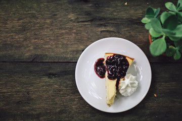 A delicious Piece of homemade cheesecake with black currant and blueberry sauce on white plate on wooden table.with fresh organic mint for dessert. Sweet summer pastry
