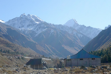 A mountain Alpine hut cabin in high Himalayas mountains, located to provide shelter to mountaineers, climbers and hikers. An interlocking overlapping spur hill ridges V-shaped valley in background.