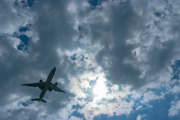 雲の多い空を飛行する一機の旅客機