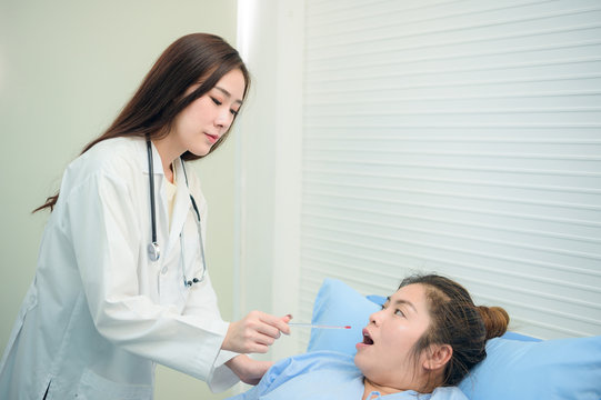 Young Inexperienced Female Doctor Taking Care Of A Fat Sick Woman On The Couch In The Medical Office. Asian Doctor And Patient Together