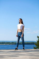 Young beautiful brunette woman posing against blue sky bright sunny weather