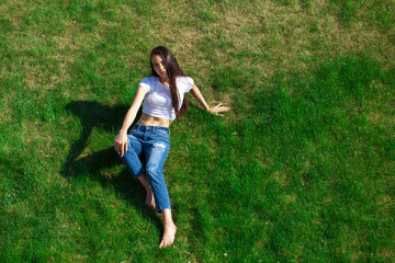 Portrait of a young beautiful girl resting on the lawn in the park