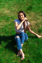 Portrait of a young beautiful girl resting on the lawn in the park