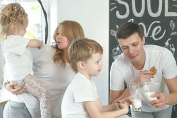 Happy family mother, father, child daughter and son having breakfast at home. Vitamine breakfast in bright kitchen room interior.