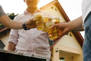 Group of happy friends drinking and toasting beer at bbq party asian person.