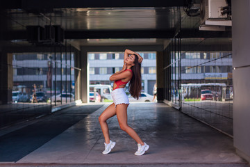 Young brunette woman dancing in arch of building.