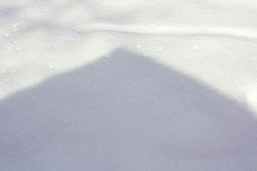 shadow on the snow from the roof of the house