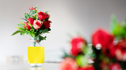Obraz na płótnie Canvas Bouquet of red plastic roses in a glass bottle placed on a wooden table. Wedding decorations, Valentine's day, home decorations Or office. Doing export business of fake flowers. copy space