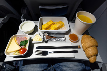 variety of food on the folding table on the plane. Late dinner during the flight at night.