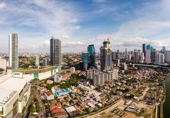 Naklejka premium Aerial view of Jakarta downtown district with a new skyscraper and other buildings in construction in Indonesia capital city. Jakarta has seen a sharp growth recently