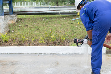worker in a blue factory suit Wear a white helmet Installing fire hose There is a grass background