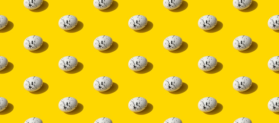 Pattern made of eggs with minimal splatter designs on yellow background