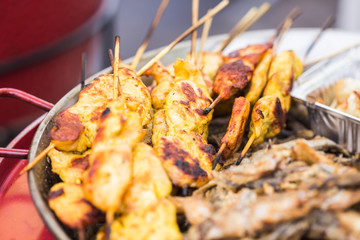 Street Food and meal concept. Grilled chickens inserted on wooden skewers was putting on street shop shelf with many other stuffs