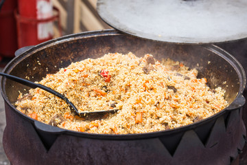 Street food festival concept - food pilaf in a cauldron close up