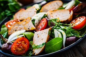 Caesar salad - barbecue chicken breast and vegetables on wooden table