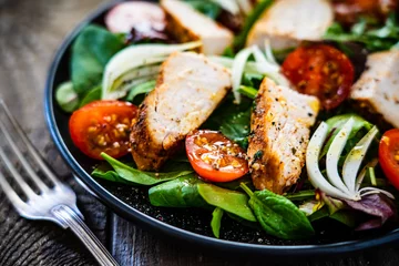 Rolgordijnen Caesar salad - barbecue chicken breast and vegetables on wooden table © Jacek Chabraszewski