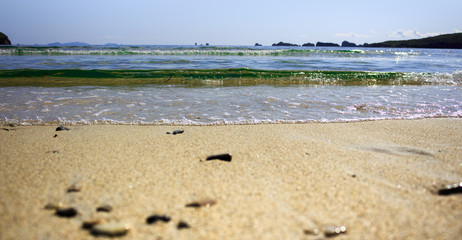 Seascape with waves, sandy beach and rocks on the horizon.