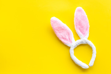 Easter bunny concept. Toy rabbit's ears for head on yellow background top-down copy space