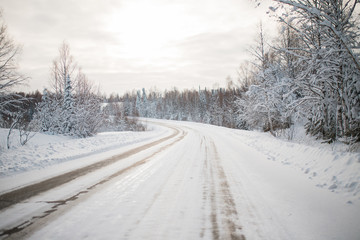 Obraz premium Winter forest. view of the snowy road. the snow on the trees. the sun is shining brightly. frosty morning in Siberia. snowy and slippery road.